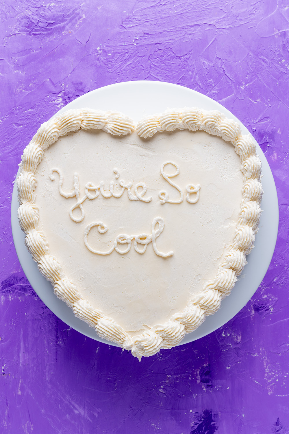 white anniversary heart cake with You're So Cool written on it.