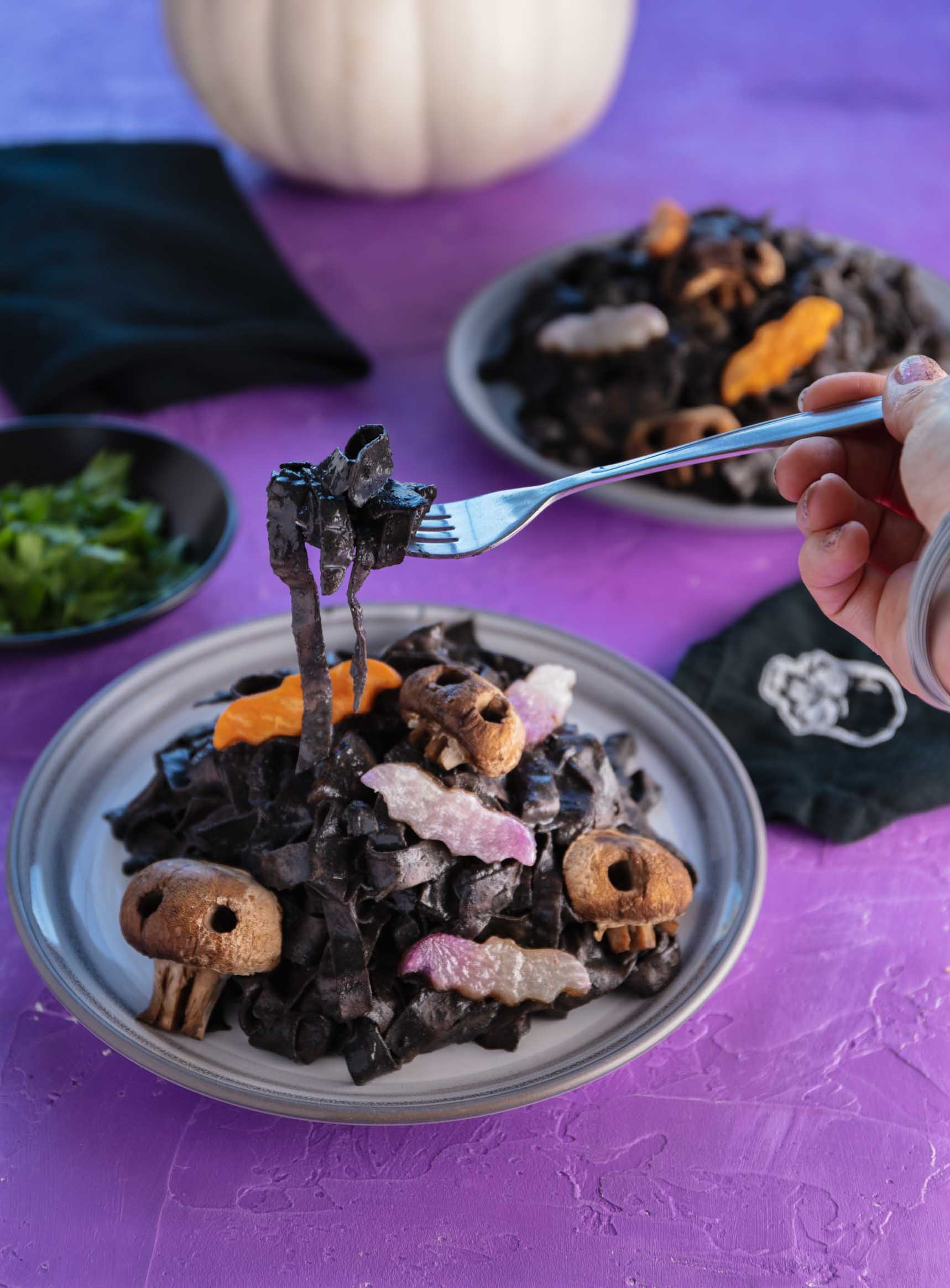 taking a bite of black halloween pasta with veggie bats and skull mushrooms