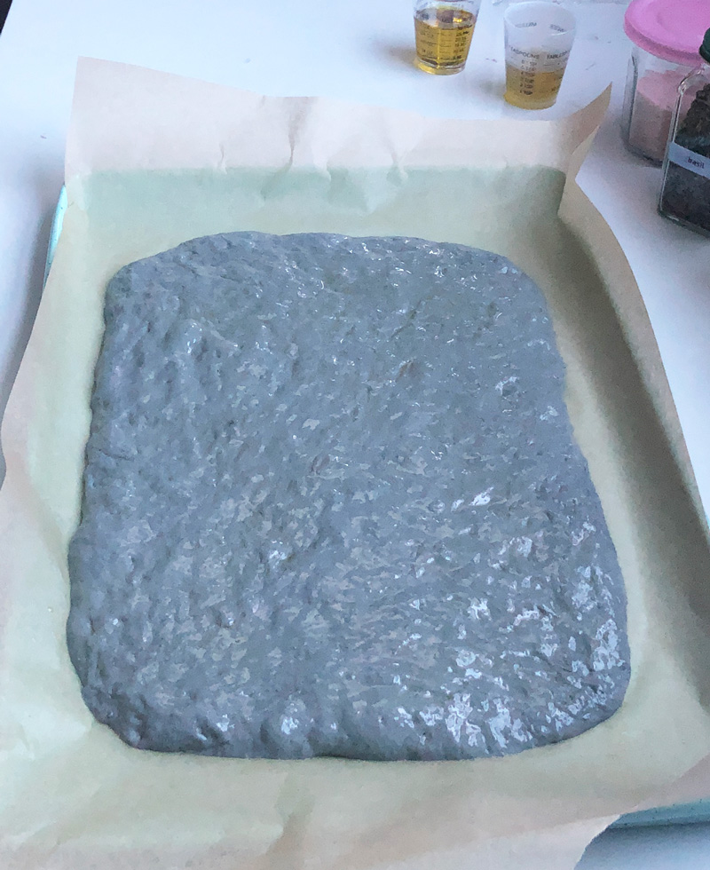spreading out the vegan focaccia dough on the baking sheet