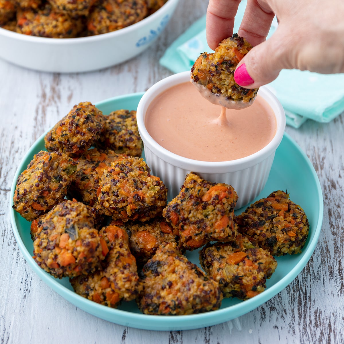 vegan millet tots dipping into some sauce.