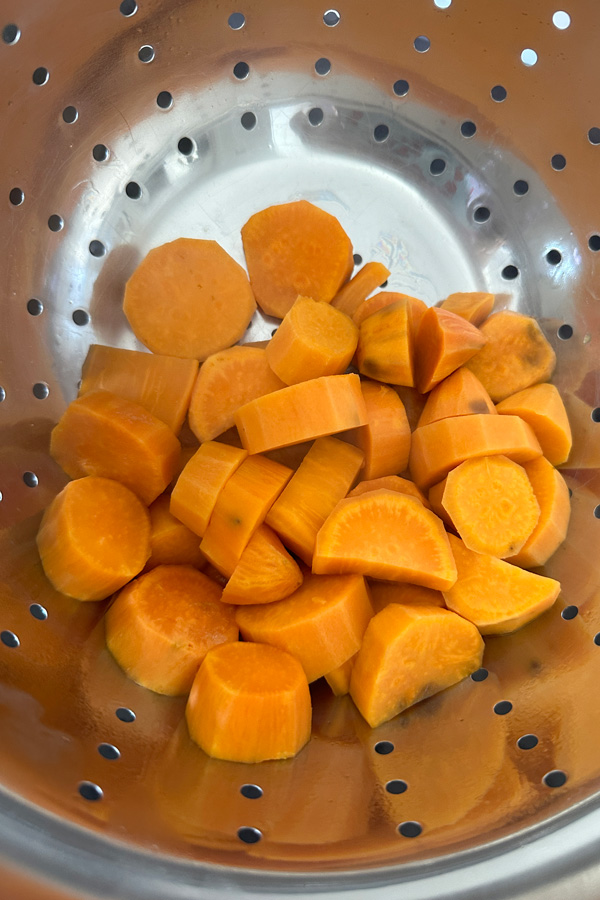 draining the vegan sweet potatoes using a colander