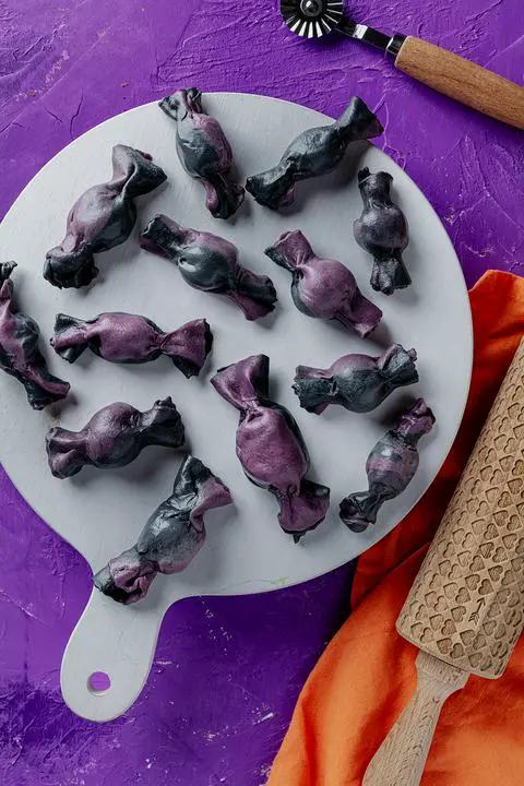 naturally colored black and purple vegan truffle ravioli shaped like wrapped candies