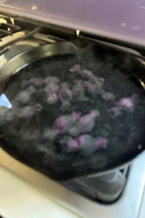 a bunch of halloween colored candy-shaped ravioli boiling in a cast iron pan
