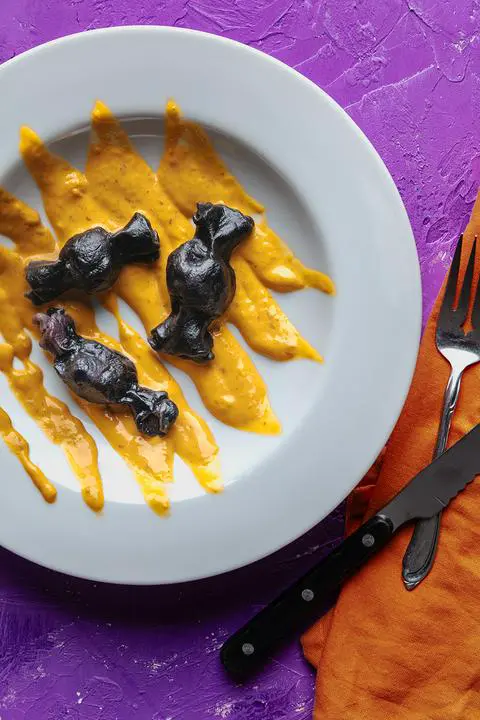 naturally colored black ravioli in an orange vegan cheese sauce