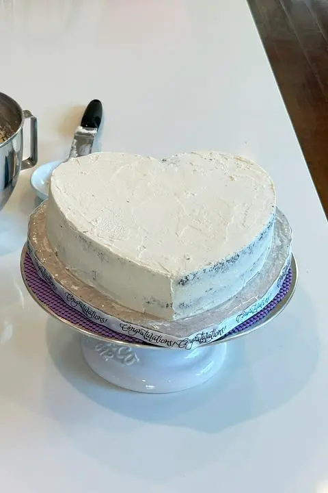 heart cake covered in a crumb coat of frosting.
