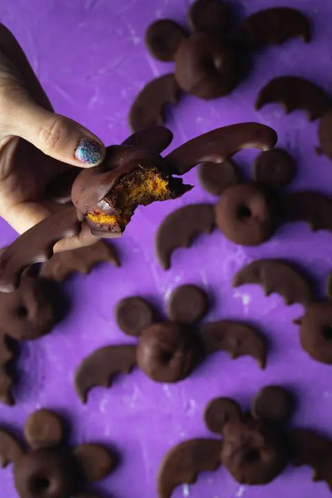 one of the mickey mouse bat halloween donuts with a bite missing showing the pumpkin spice cake donut inside