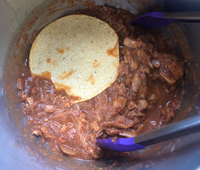 dipping the tortillas into the birria consommé