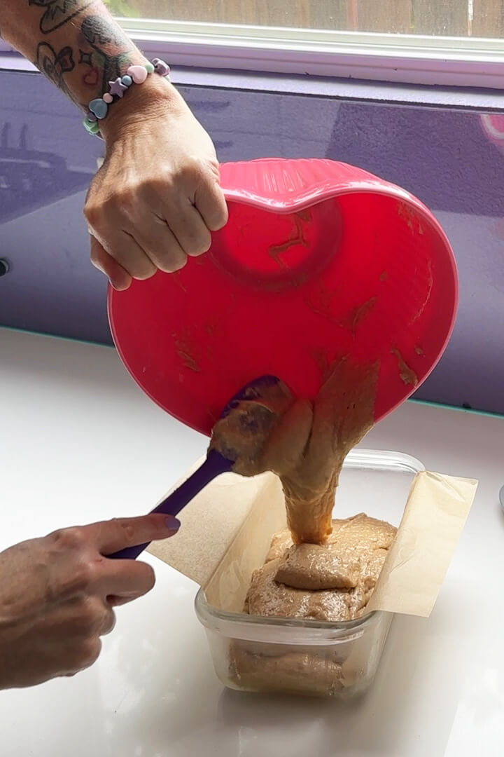 transferring the thick biscoff cake batter into the parchment lined loaf pan