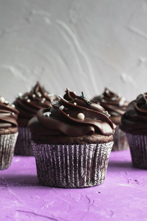 a vegan brooklyn blackout cupcake with a spiderweb cupcake paper and a purple a gray background
