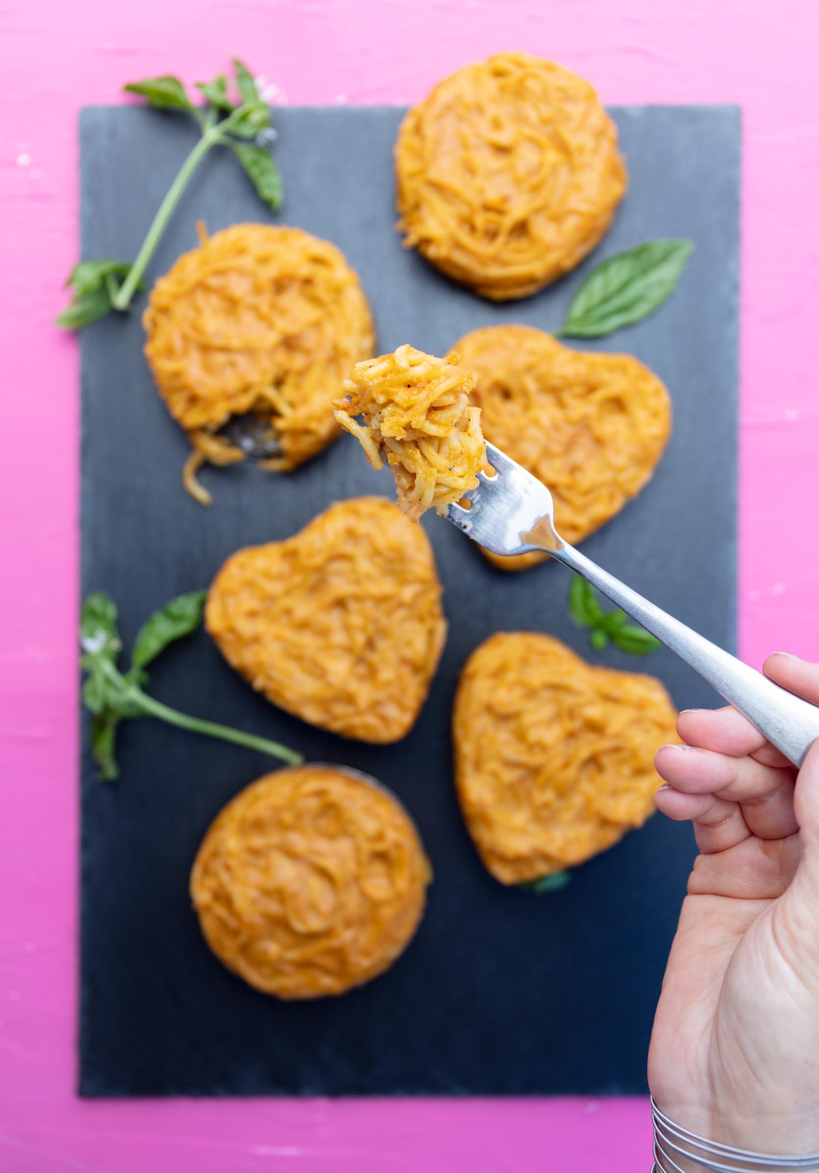 taking a bite of one of the heart shaped vegan cacio e pepe mini cakes