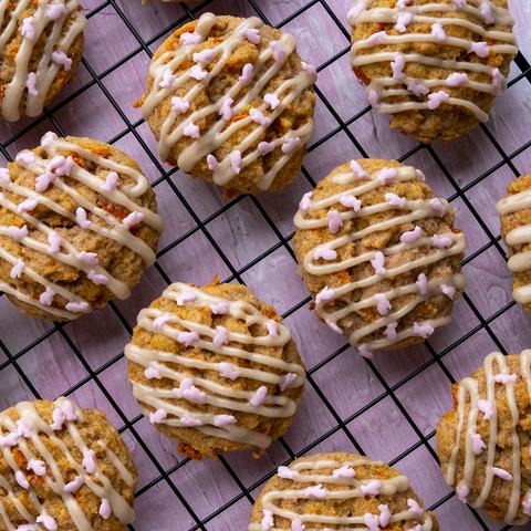 carrot cake cookies on a cooling rack with cream cheese icing drizzle and pink bunny sprinkles