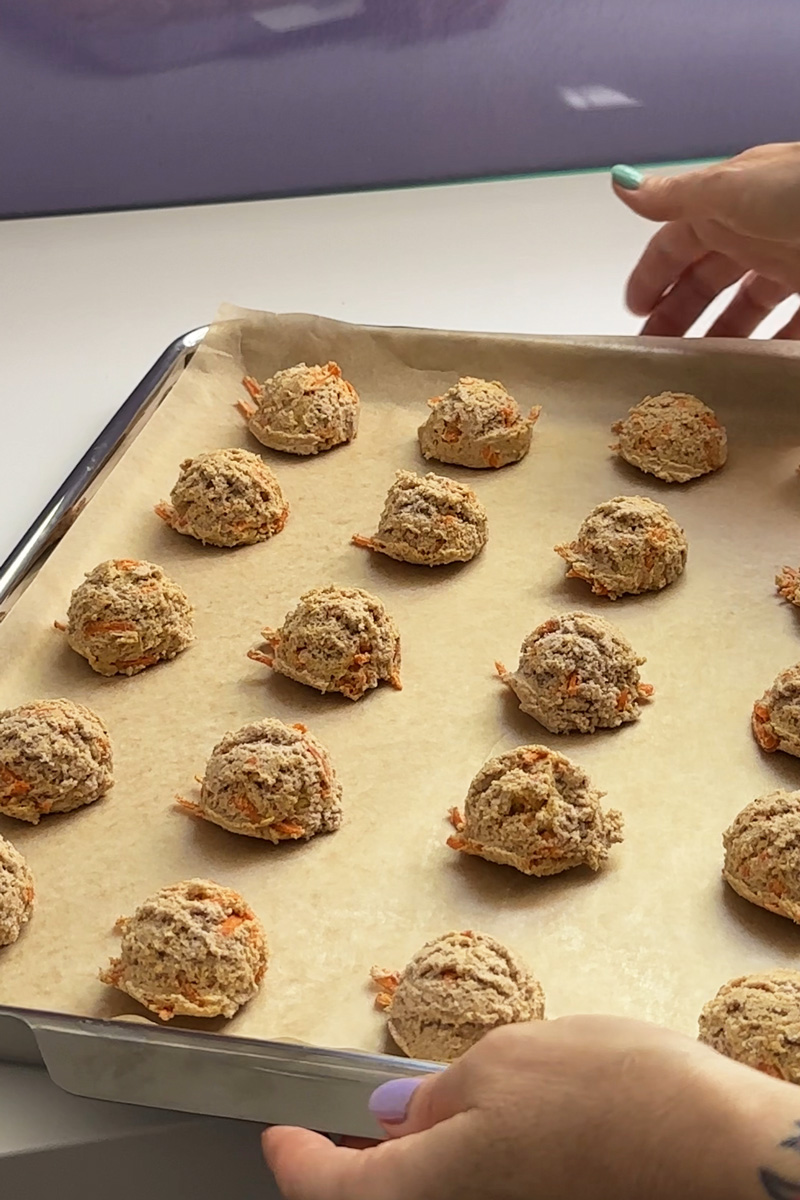 a baking sheet lined with parchment paper with 20 balls of cookie dough on it.