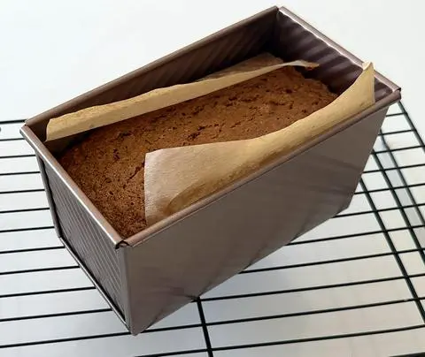 the carrot cake loaf baked and cooling in the pan on a cooling rack.