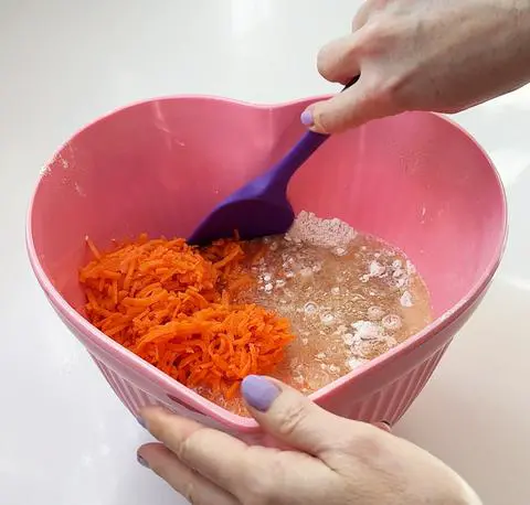 mixing the carrots and the wet ingredients with the dry ingredients.