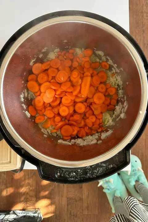 adding carrots to the carrot celery soup.
