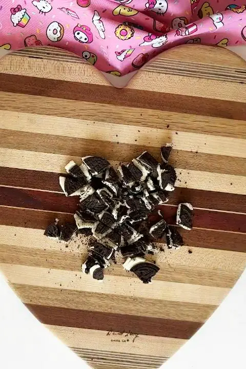 chopped vegan chocolate sandwich cookies on a heart-shaped cutting board.