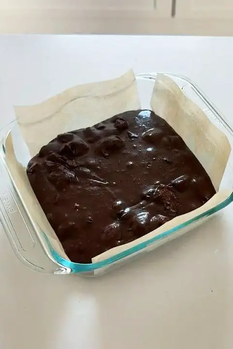 the vegan brownie batter in the glass pan lined with parchment paper.