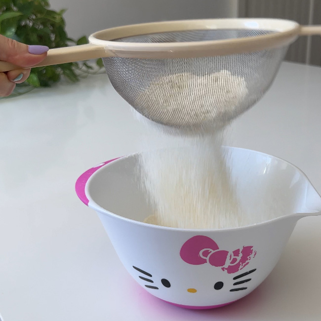 sifting dry ingredients for the plant-based chocolate chip muffins