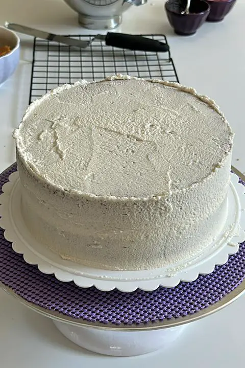 vegan biscoff cake covered in a crumb coat of frosting.