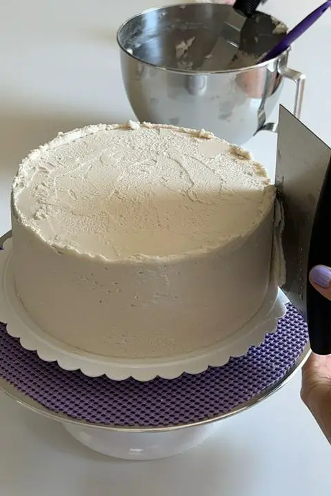 Smoothing out the final coat of white frosting on the cake.