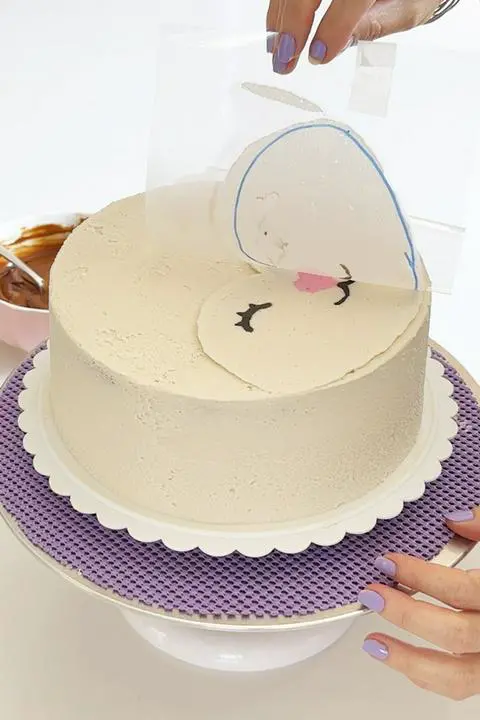 peeling the acetate off the cake, leaving the deer face on the cake.