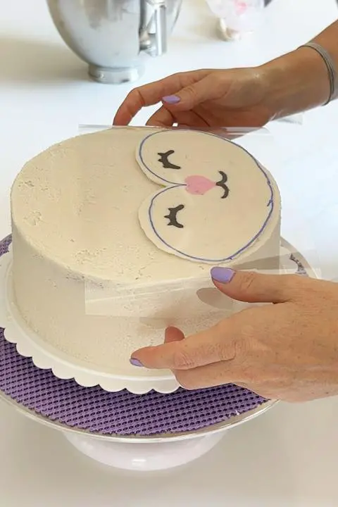Pressing the buttercream transfer onto the top of the cake.