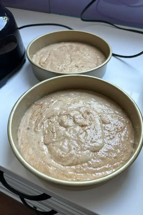 2 cake pans filled with vegan biscoff cake batter.
