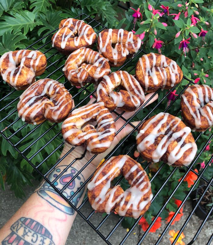 Cinnamon roll donuts with icing on a cooling rack in the yard