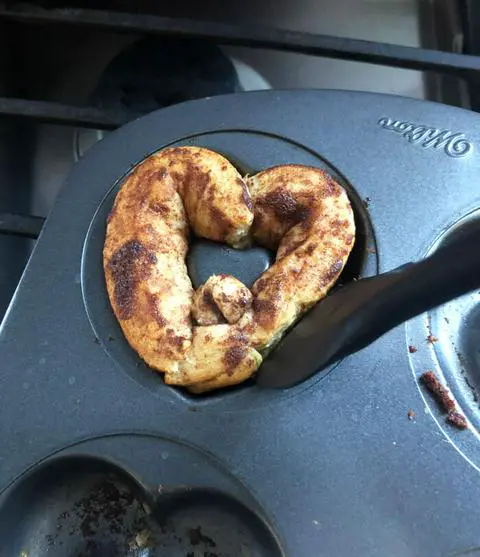 using a silicone spatula to remove a cinnamon roll donut form the donut pan