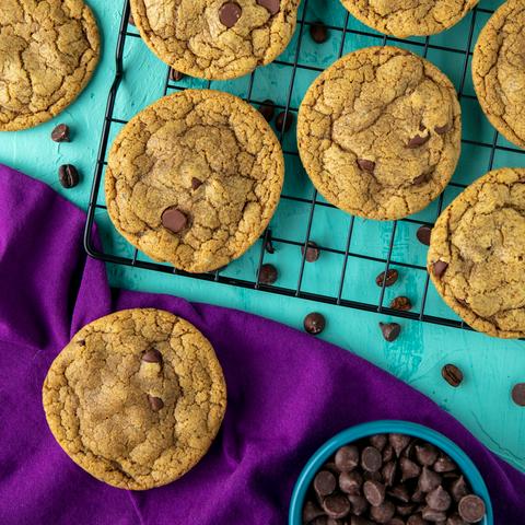 coffee chocolate chip cookies on a cooling rack with one on a purple napkin