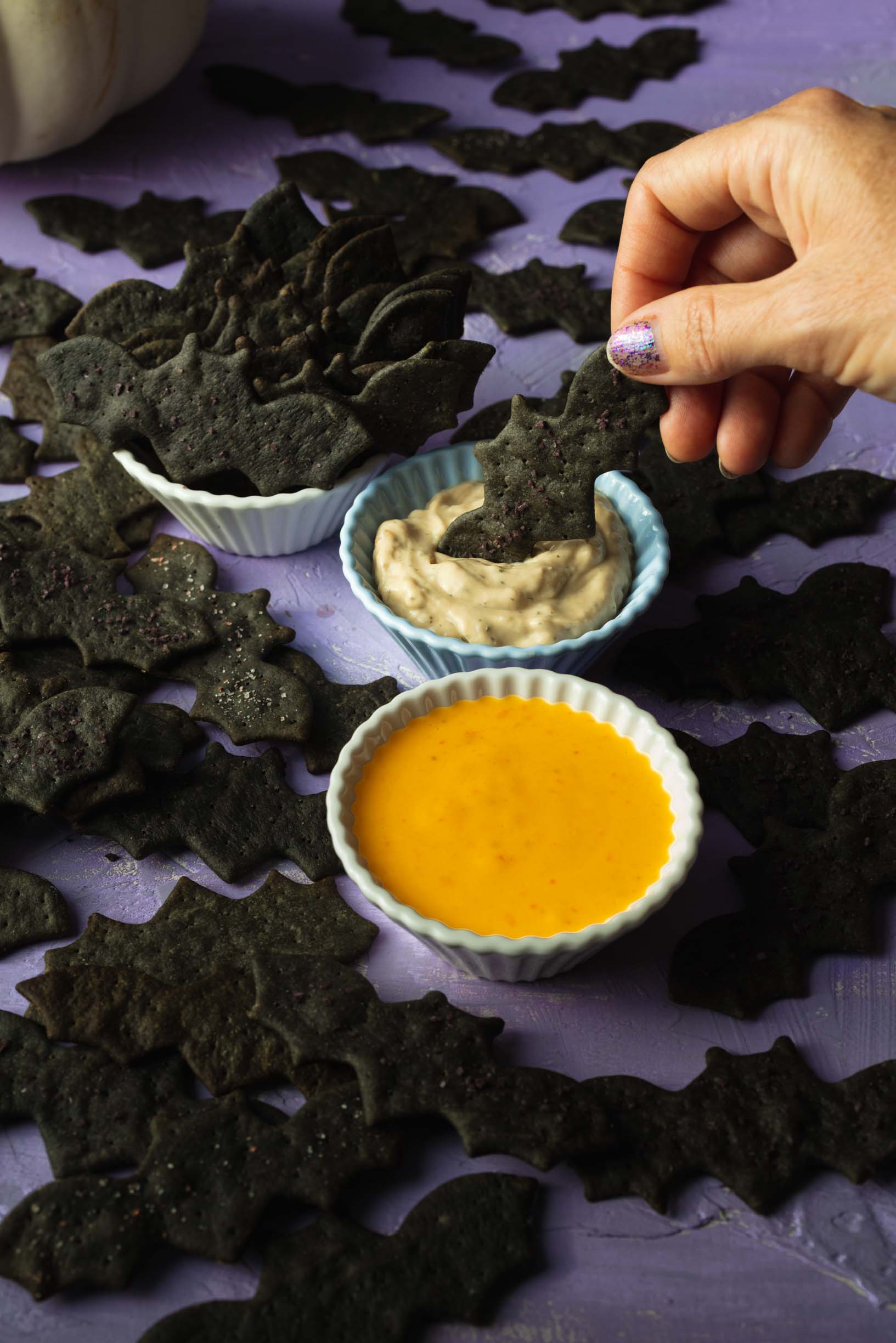 dipping a vegan black tahini bat cracker into dip