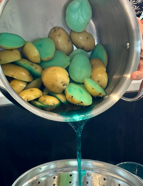 pouring the boiled teal potatoes into a colander in the sink