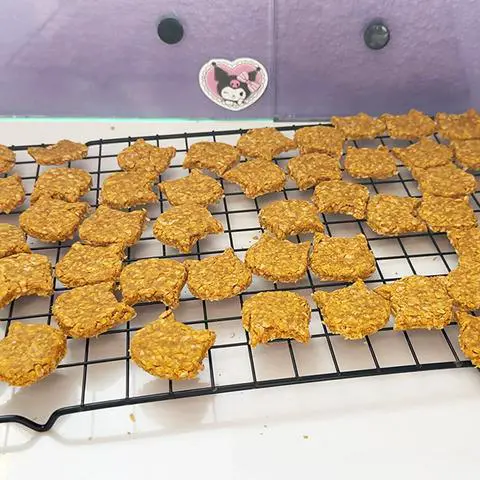 cat shaped dog treats on a cooling rack.