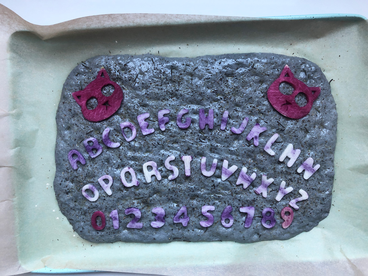 vegan focaccia decorated with ouija board halloween focaccia art