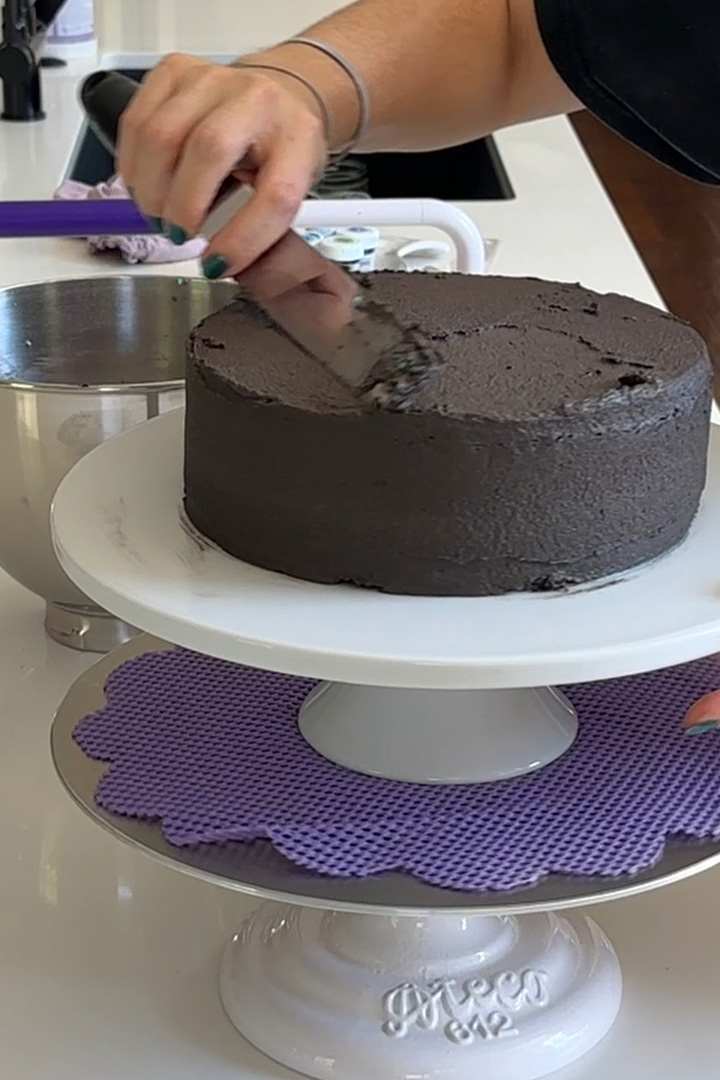 covering the galaxy cake with black chocolate buttercream frosting