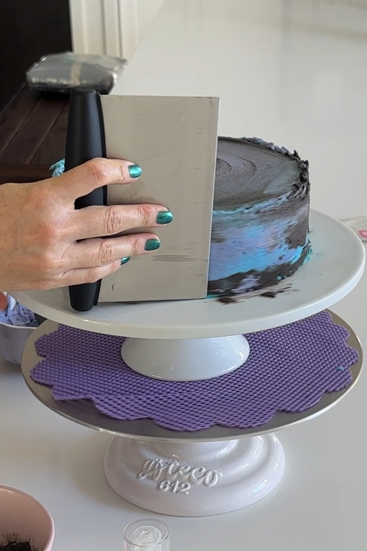 covering the vegan galaxy cake with galaxy chocolate and vanilla buttercream frosting