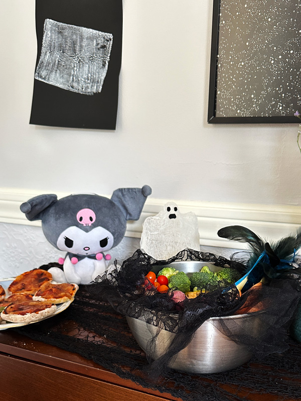 a table with random Halloween decorations and mini vegan pizzas