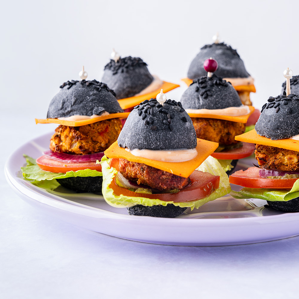 mini burgers with black buns on a plate