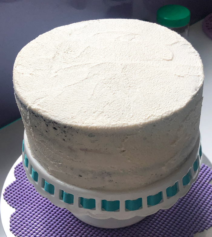 vegan graduation cake covered in a crumb coat of vegan vanilla frosting