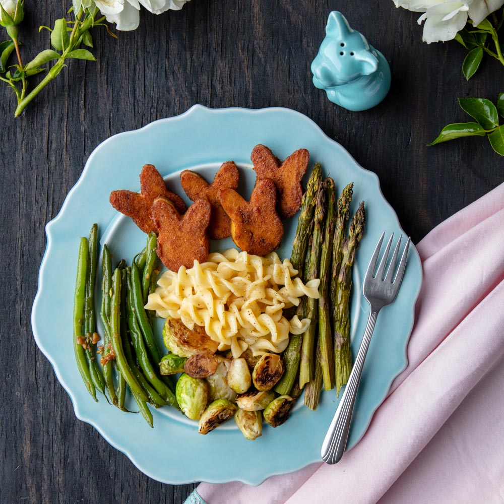 bunny-shaped vegan ham on a plate with veggies and mac n cheese