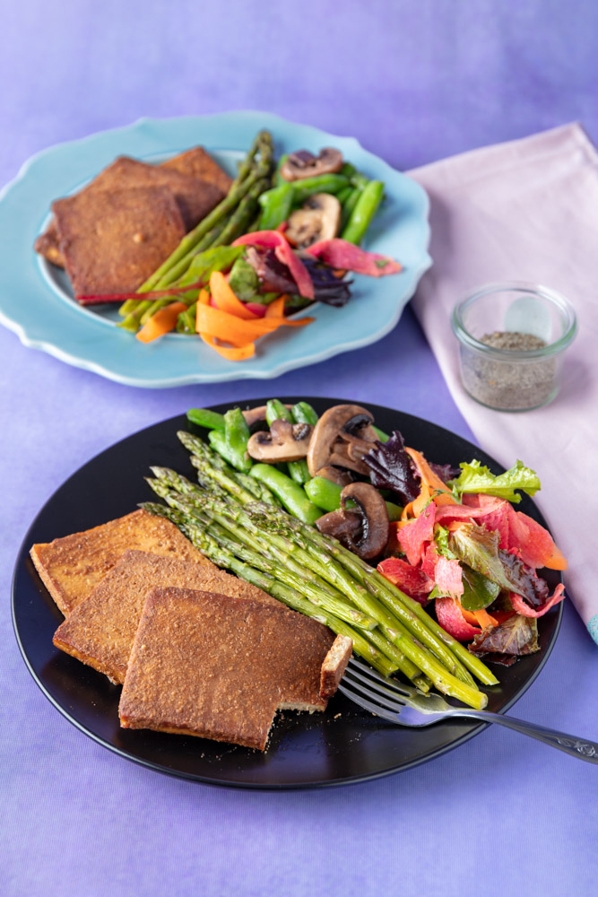 vegan ham slices on a plate with veggies and salad
