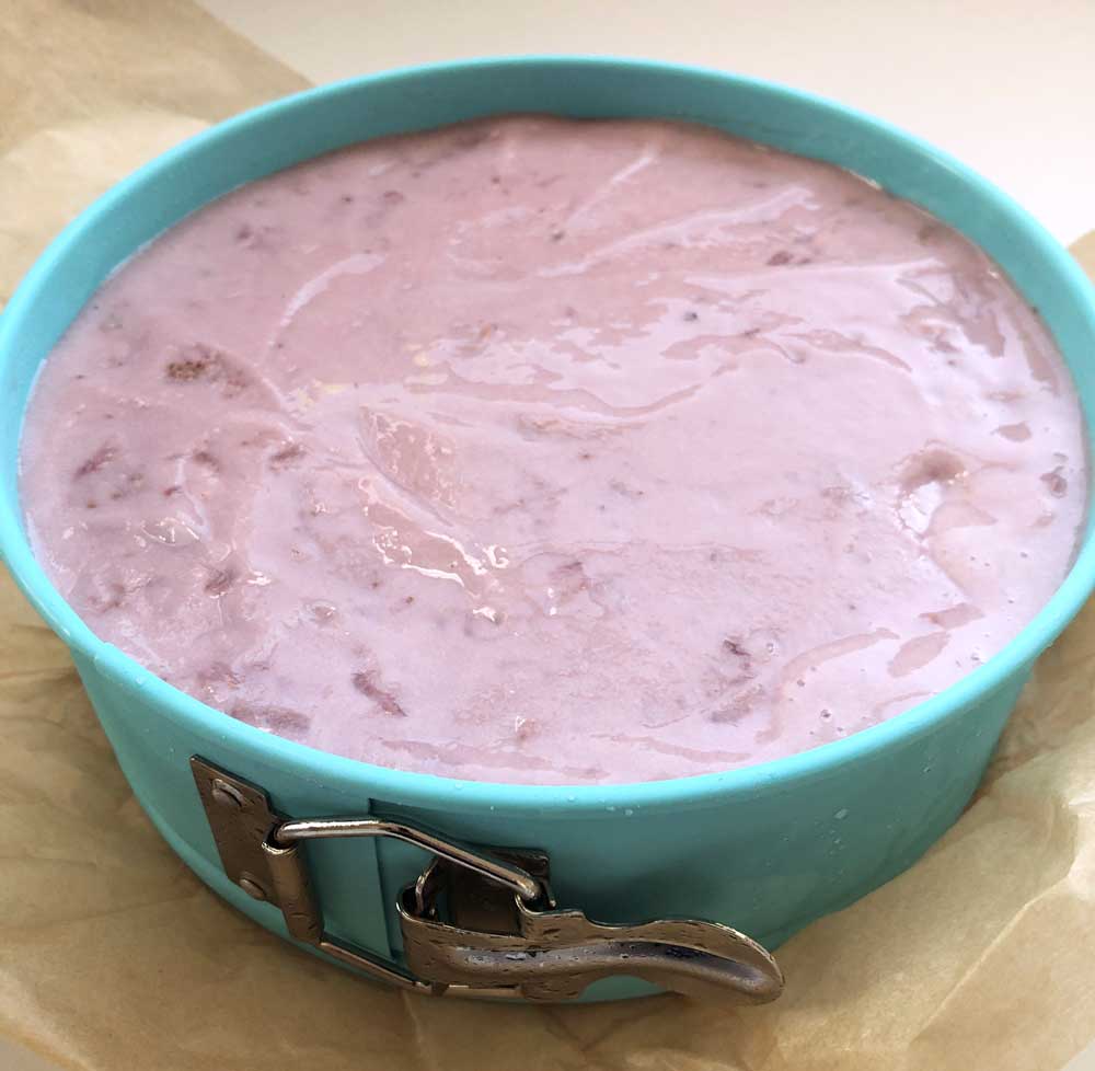 vegan strawberry ice cream being added to the springform pan