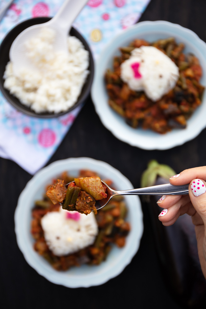 two bowls of kara kuzhambu or kara kulambu, each with a hello kitty made of white rice with a bite of one bowl held close to the camera