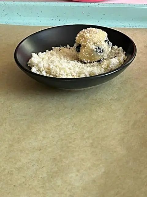 rolling the lemon blueberry cookies in lemon zest sugar before baking