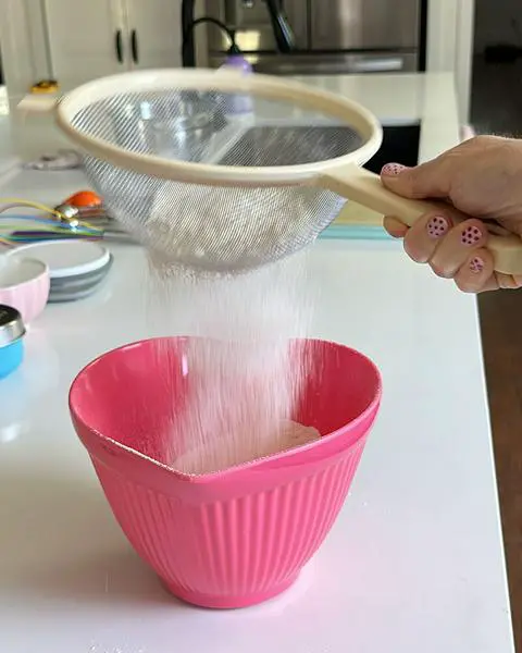 sifting dry ingredients for the lemon blueberry cookies