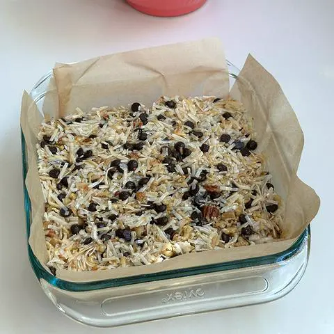 square glass baking dish filled with magic bar filling and ready to decorate and bake.