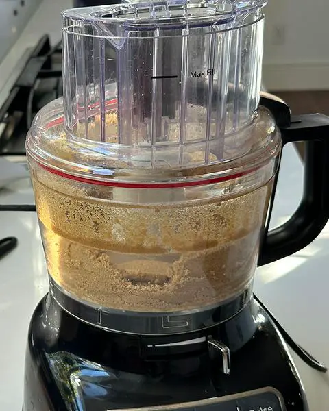 a food processor with graham cracker crust inside.