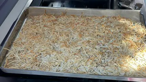 a baking tray with toasted coconut in it.