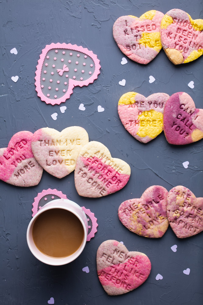 valentine cookies stamped with song lyrics next to a cup of coffee