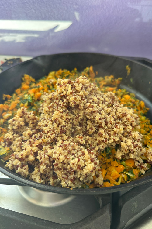 mixing the cooked millet and quinoa with the veggies